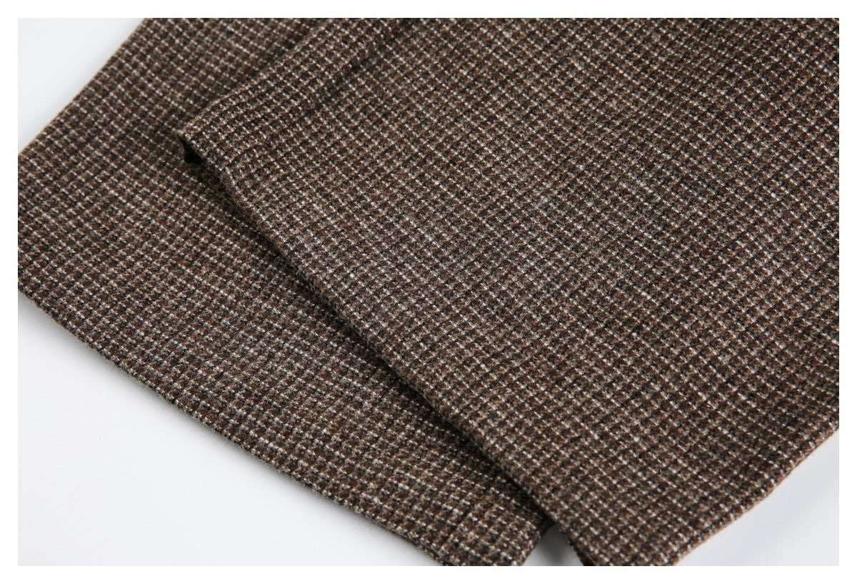 Close-up of brown check fabric showing overlapping garment panels and a small stitched opening.