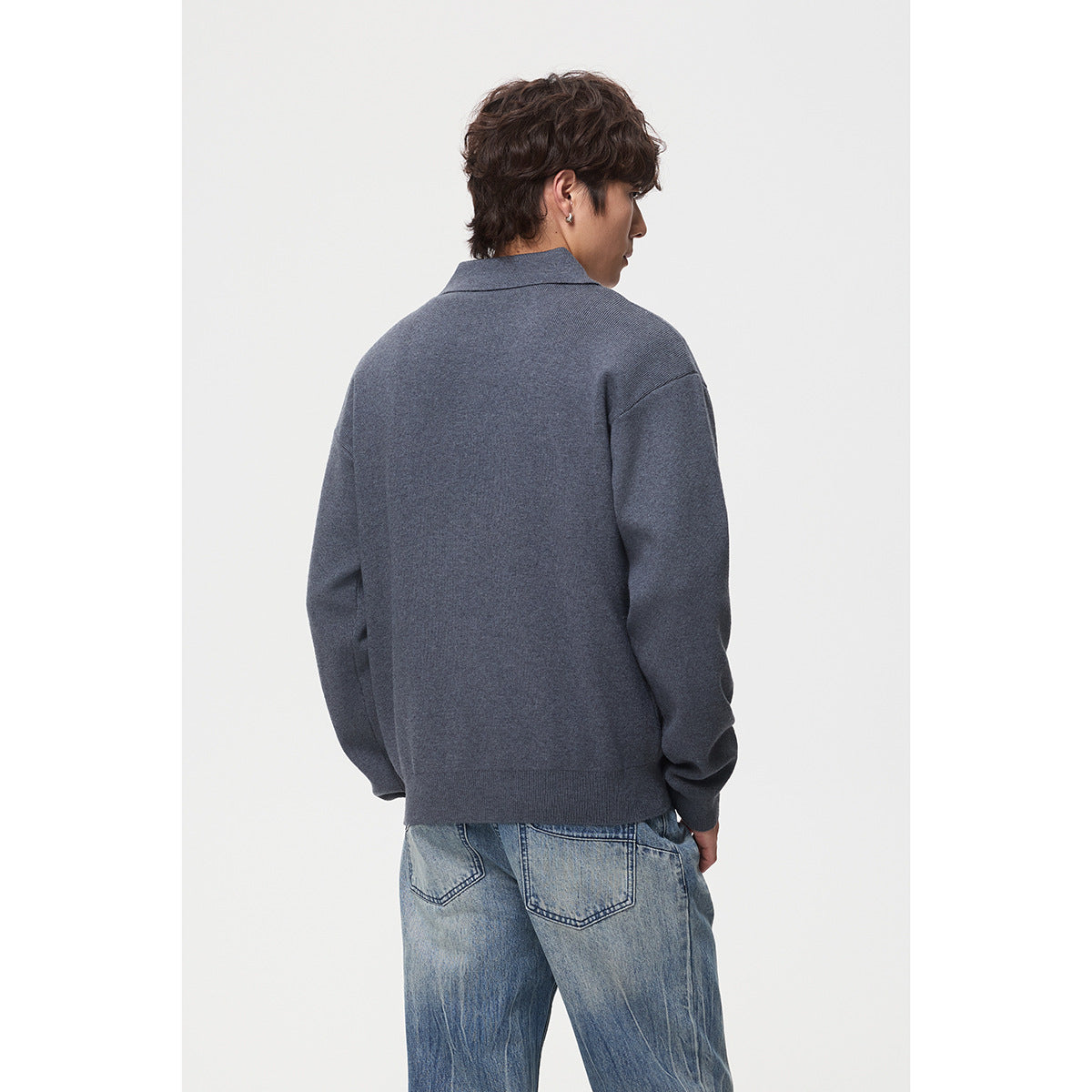 Rear view of a model wearing a slate-blue long-sleeve collared pullover with light-wash jeans.
