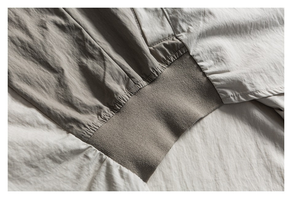 Close-up of a taupe ribbed cuff joined to the sleeve of a light neutral garment.