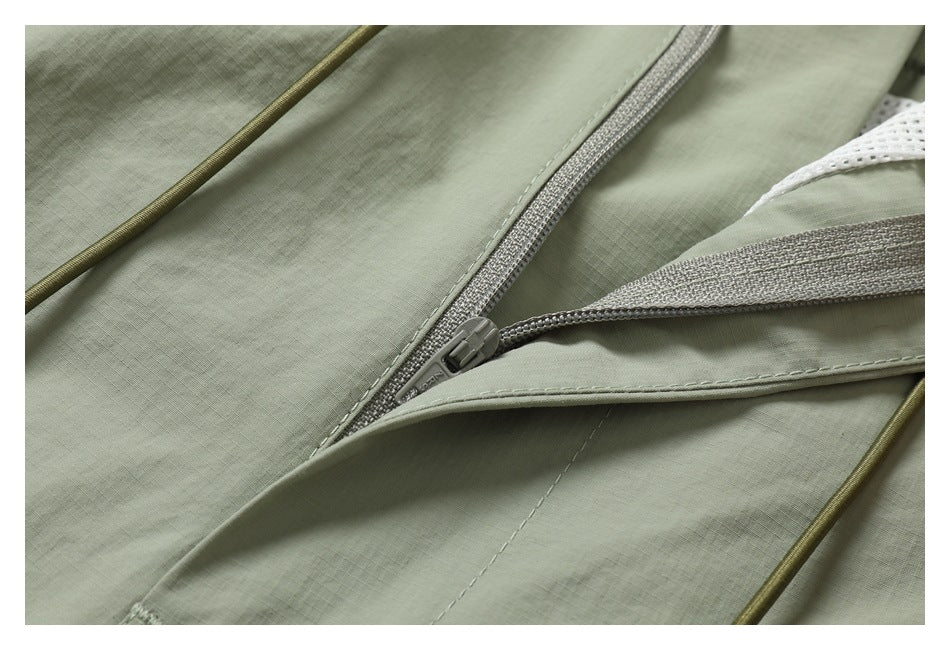 Close-up of sage pants showing a gray zipper beneath a fabric flap and olive drawcords.