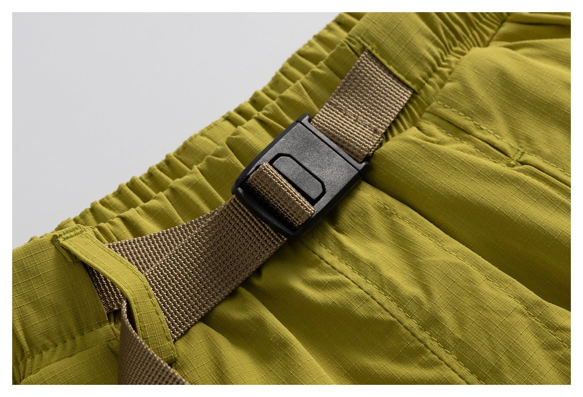 Close-up of an olive-yellow elastic waistband and brown webbing belt with a black buckle.