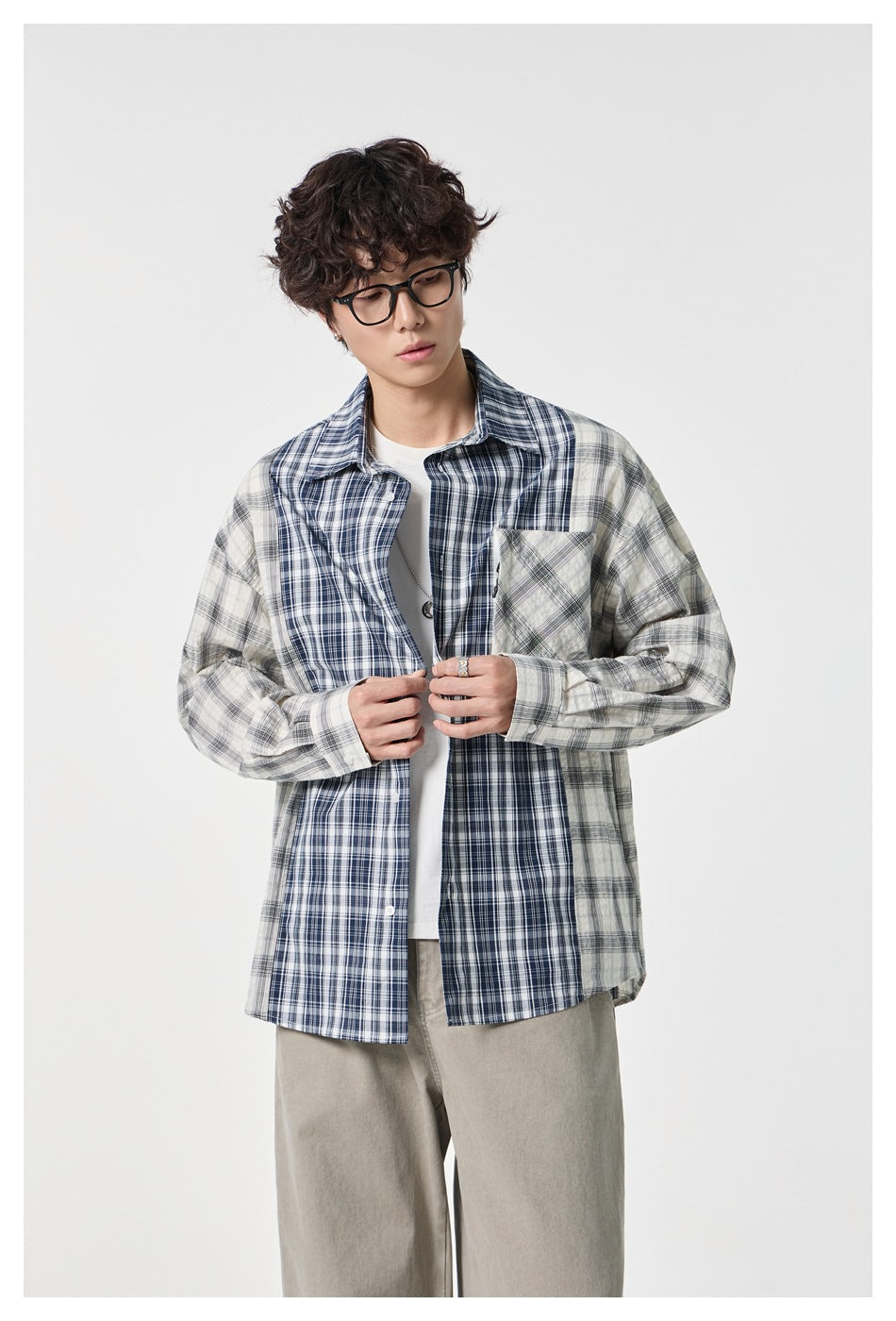 Model in blue and white plaid patchwork shirt buttoning it over a white tee, upper-body view