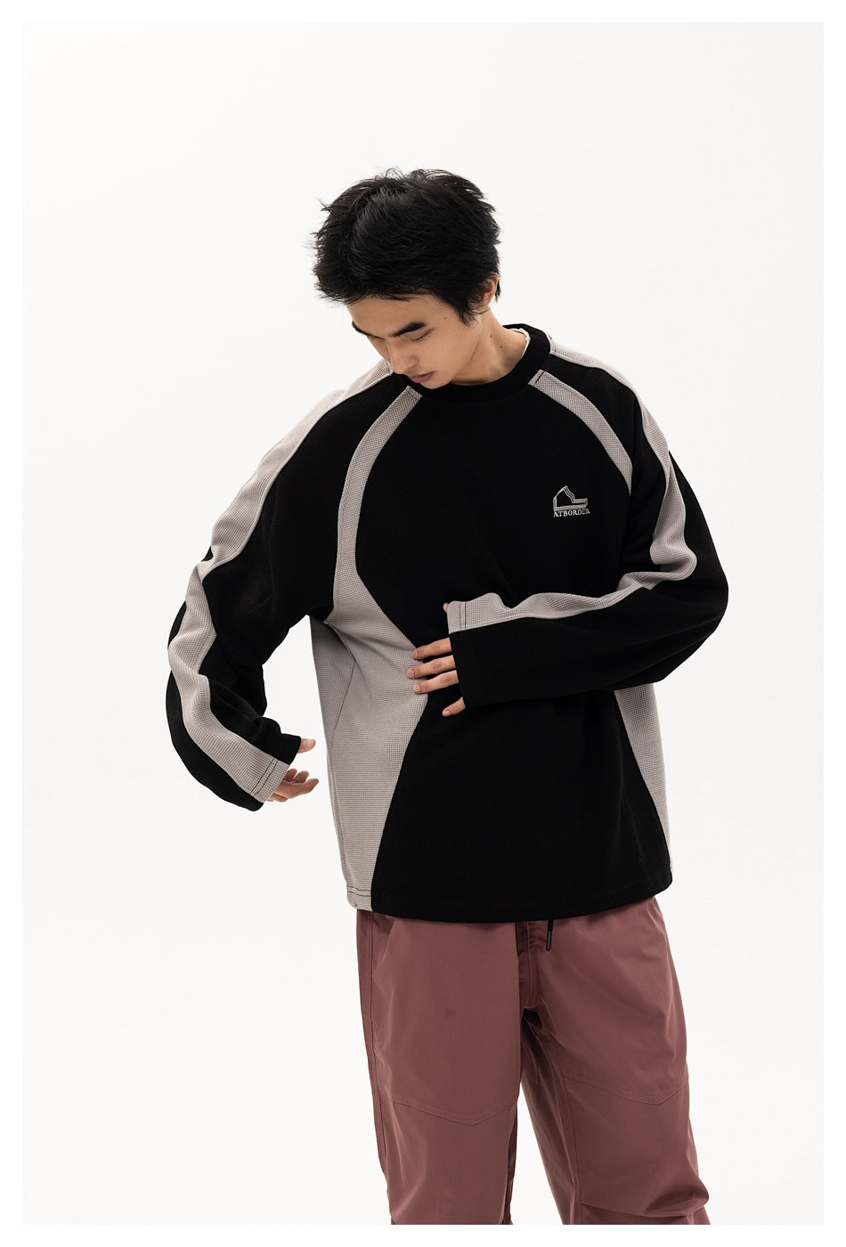 Model in black and gray raglan sweatshirt, close view of sleeves, side panels and chest logo