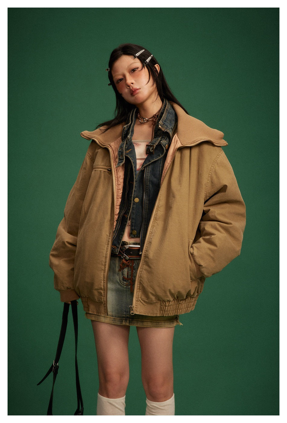 Model wearing an oversized camel-brown zip jacket with a wide ribbed collar, elastic hem, and front pockets.