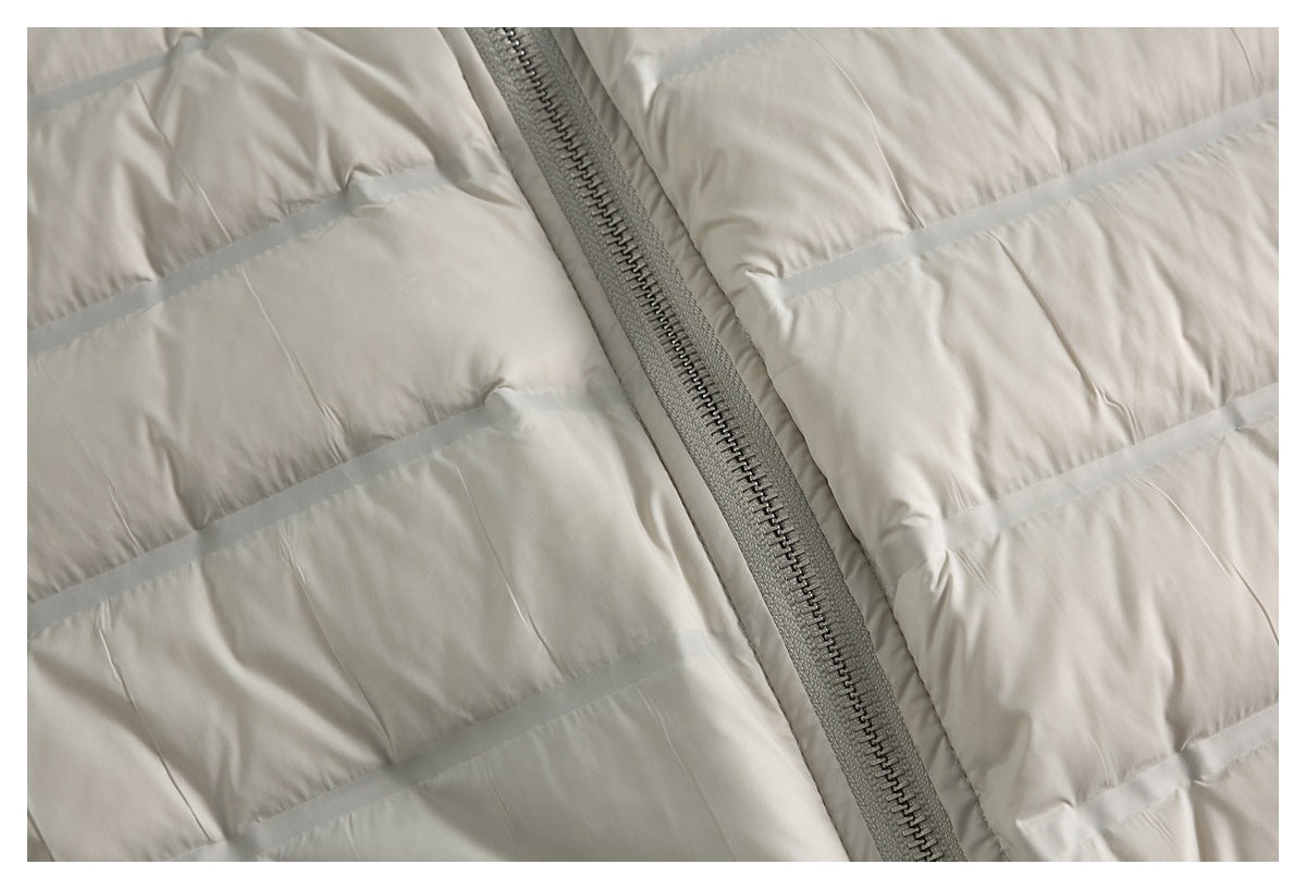 Close-up of the gray zipper and horizontal quilting on a cream puffer jacket.