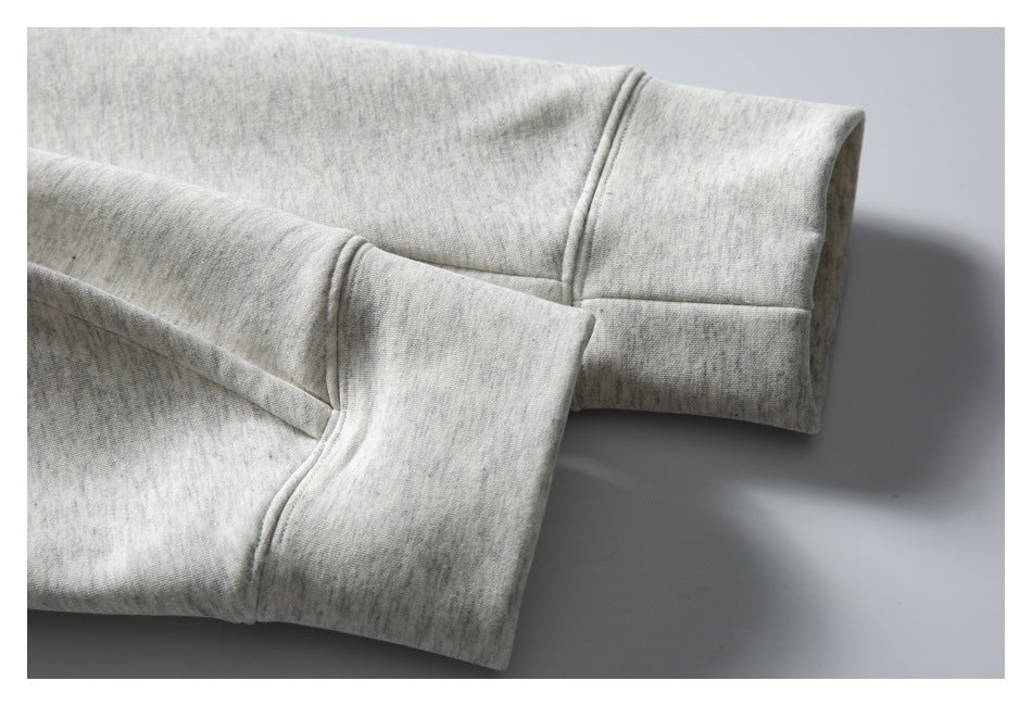 Close-up of the wide cuff and stitched sleeve seam on a light gray marled sweatshirt.