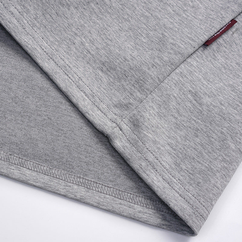 Close-up of the heather gray polo shirt's stitched hem and a small red side tag.