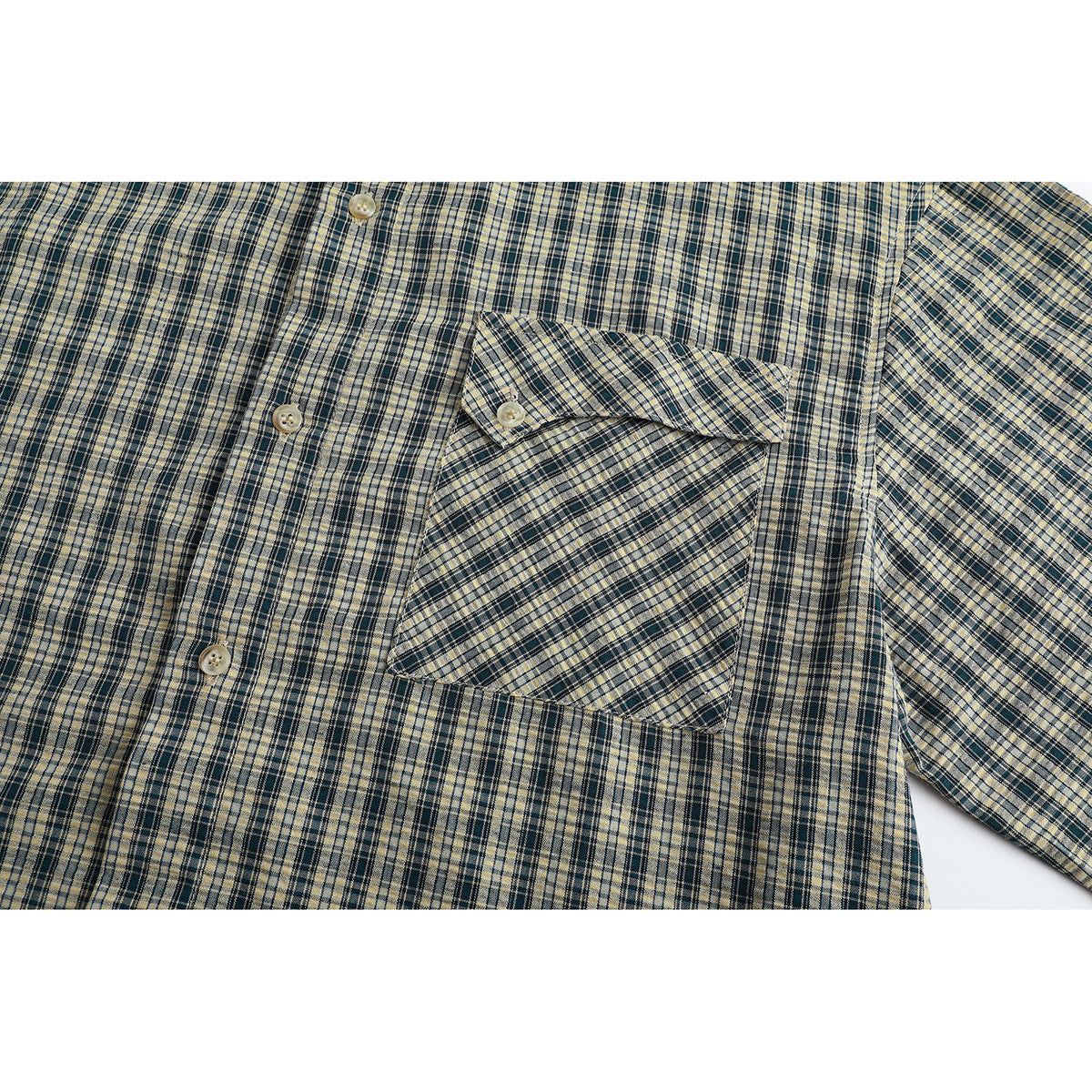 Close-up of the plaid shirt's button front, long sleeve, and single chest pocket with a buttoned flap.