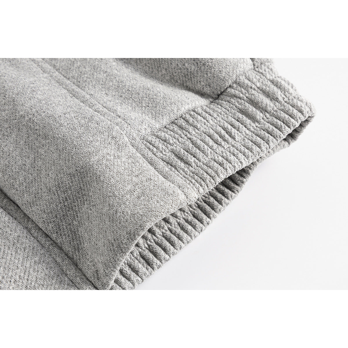Close-up of the gray jacket's textured fabric and gathered elastic hem.