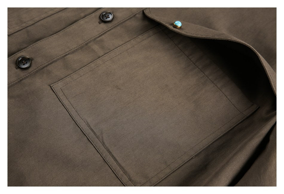 Close-up of a brown garment with a large rectangular patch pocket, dark buttons, and a small turquoise button detail.