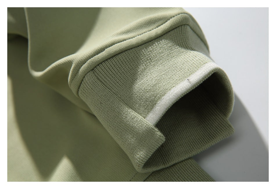 Close-up of a pale sage-green sweatshirt sleeve cuff with a narrow white stripe.