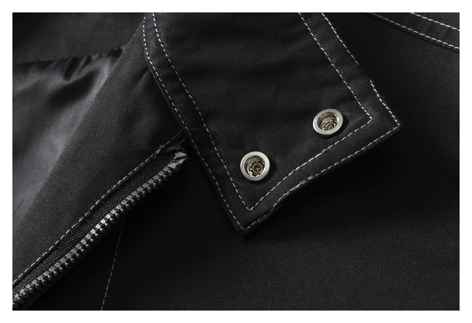 Close-up of a black garment's zipper and snap-fastened flap with contrast stitching.