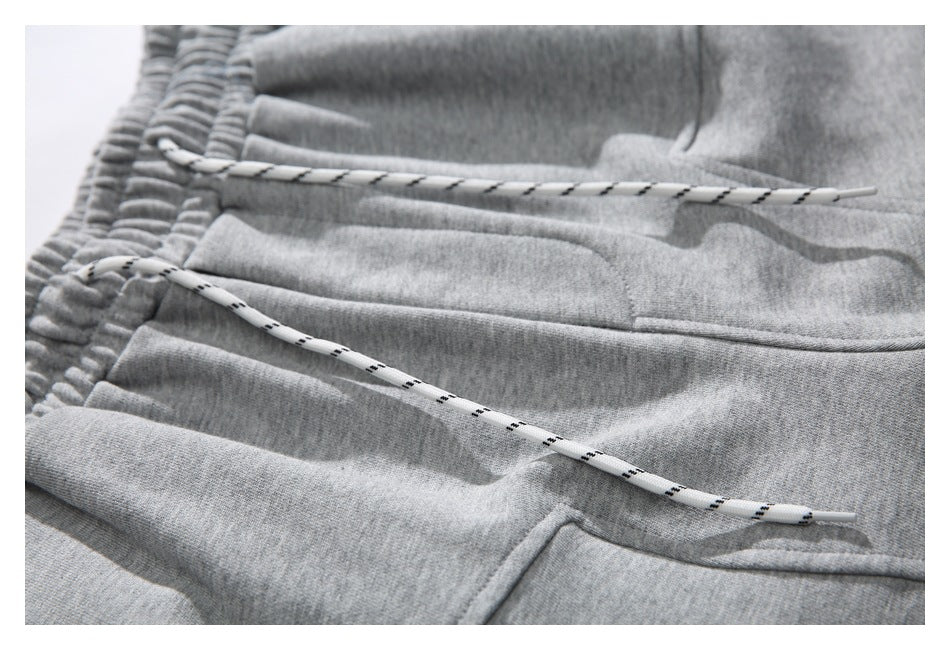 Close-up of gray shorts with a gathered waistband, patterned white drawstring, and front pocket seams.
