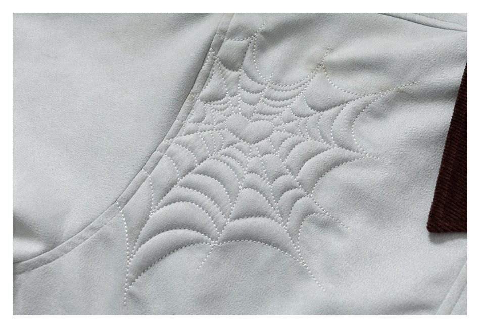 Close-up of decorative curved quilt stitching on the light gray jacket shoulder.