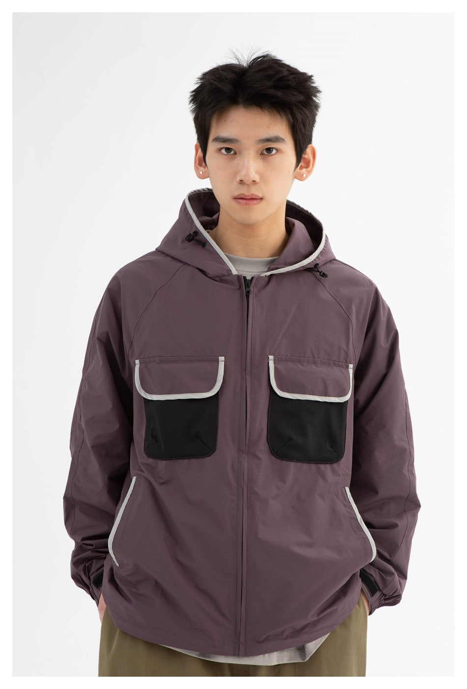 Close front view of a model wearing a plum hooded jacket with black chest pockets and light contrasting trim.