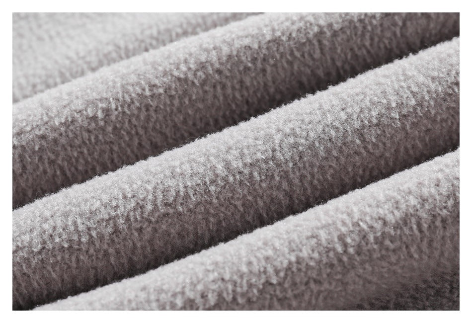 Extreme close-up of pale gray fuzzy fabric arranged in soft diagonal folds, showing its plush surface texture.