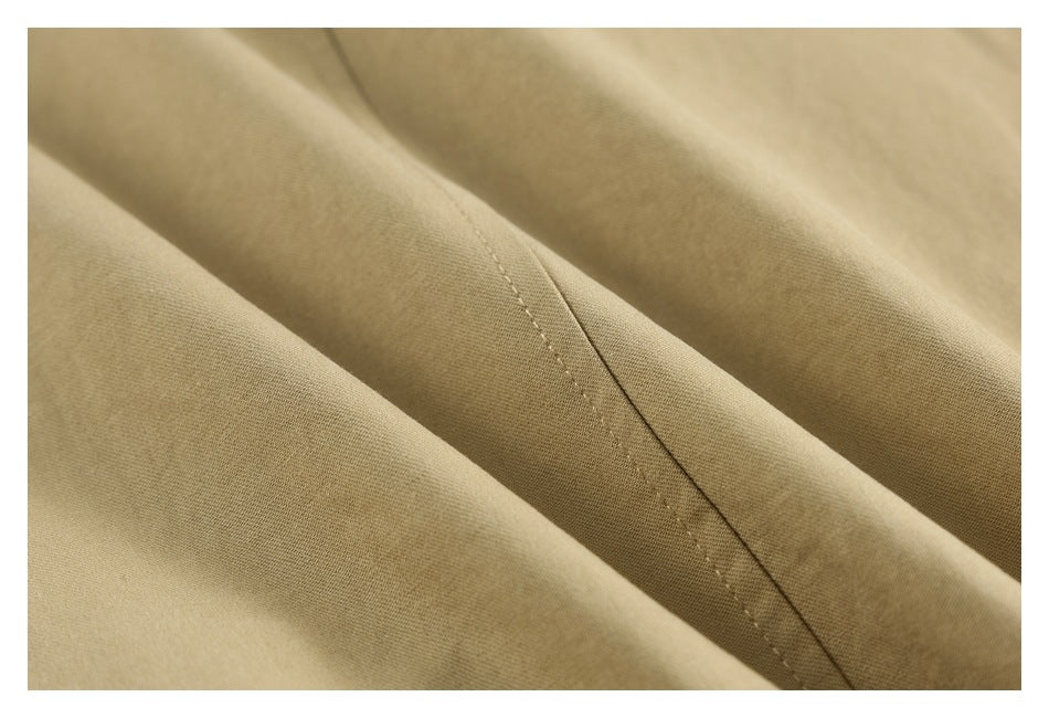 Close-up of a diagonal stitched seam across folded beige garment fabric.