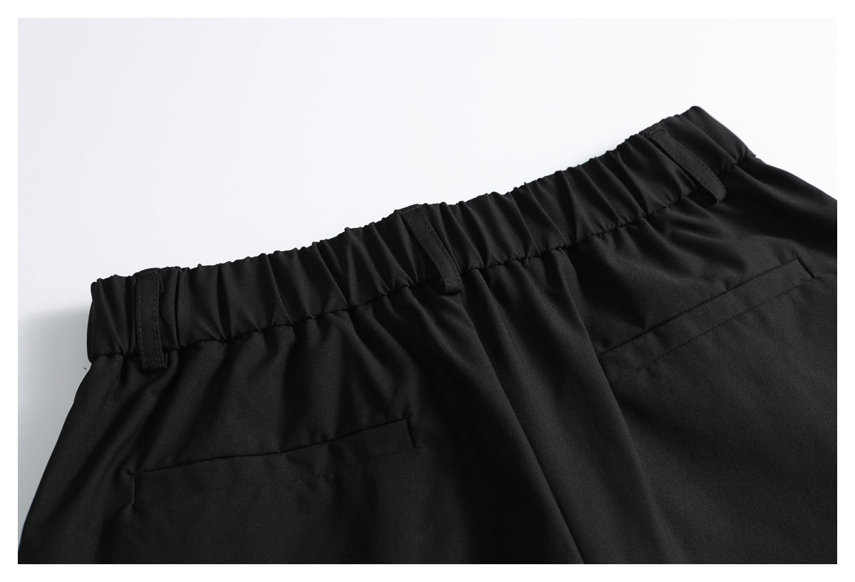 Cropped rear view of black trousers with a gathered waistband, belt loops, and welt pockets.