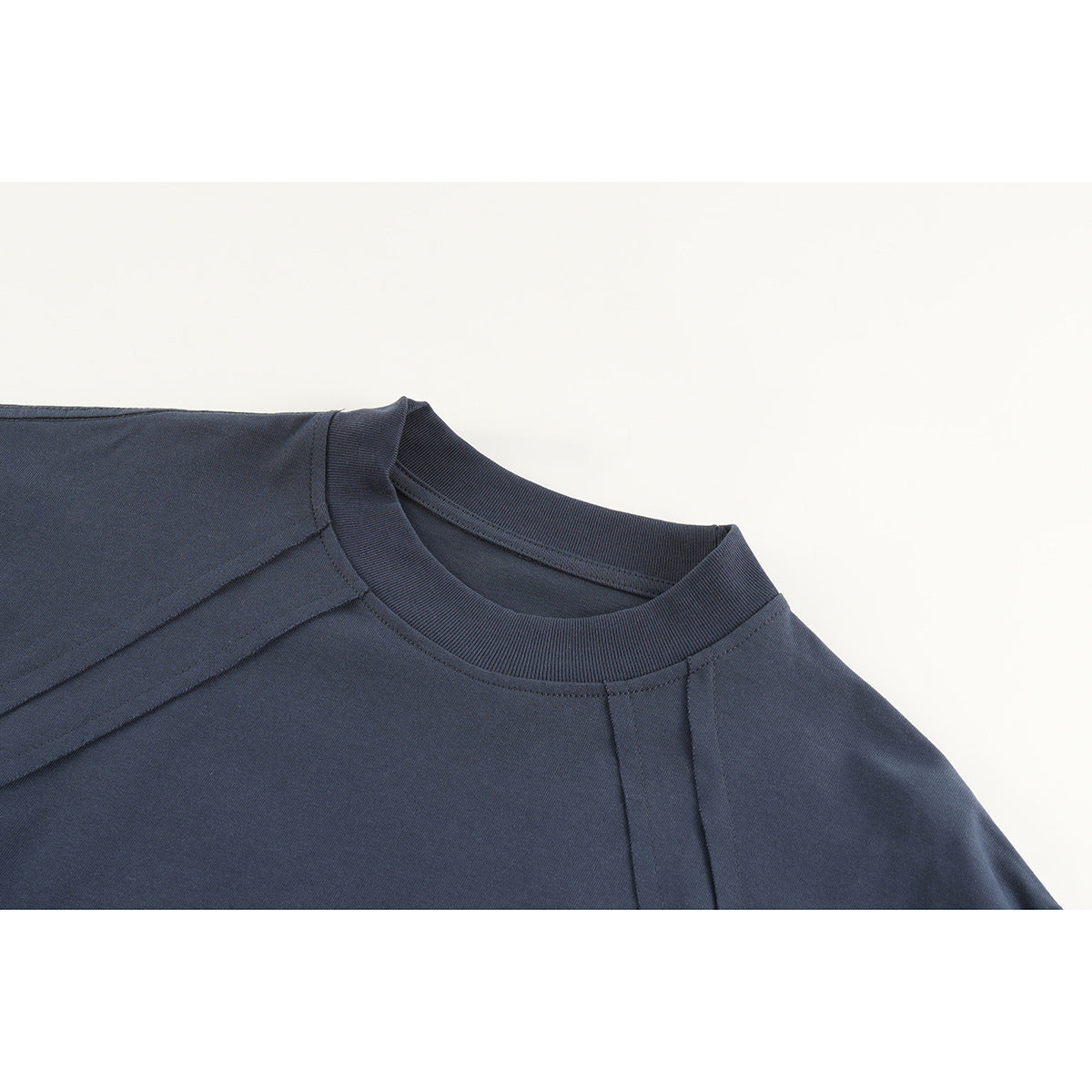 Close-up of a navy long-sleeve shirt's ribbed crew neckline and shoulder seams.
