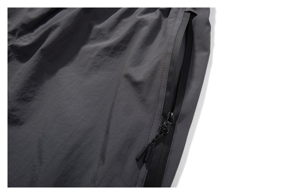 Close-up of a charcoal shorts side pocket with a black zipper and pull tabs.