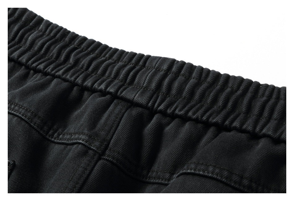 Close-up of black pants with a gathered elastic waistband and visible stitching.