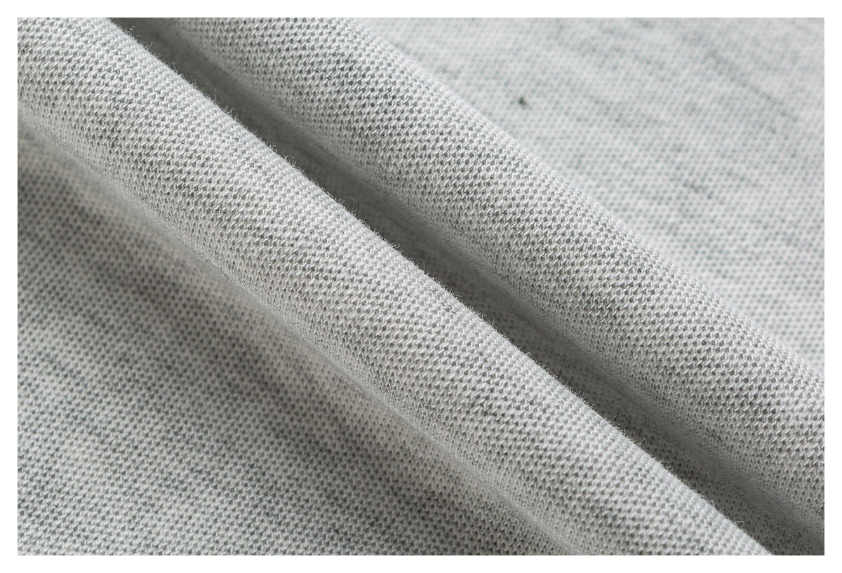 Macro view of light gray knit fabric draped in folds, showing its textured weave.