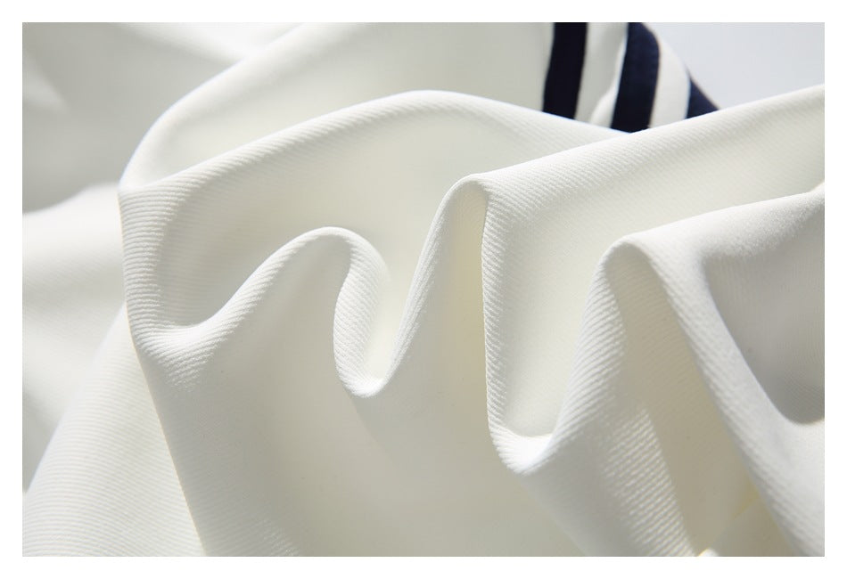 Macro view of the white garment's textured fabric, with navy stripes in the background.