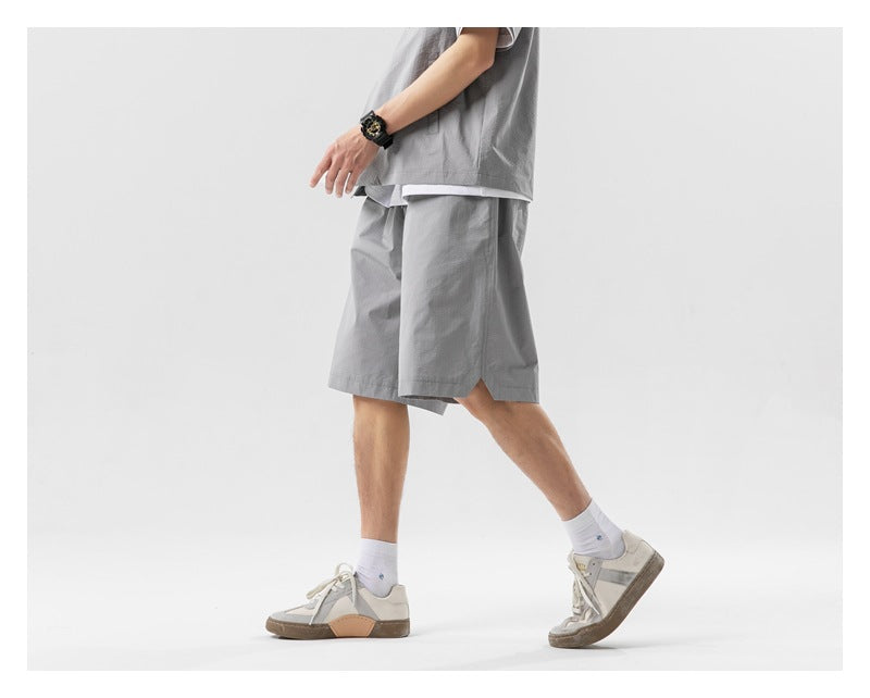 Side view of a model walking in light gray knee-length shorts and a matching shirt.