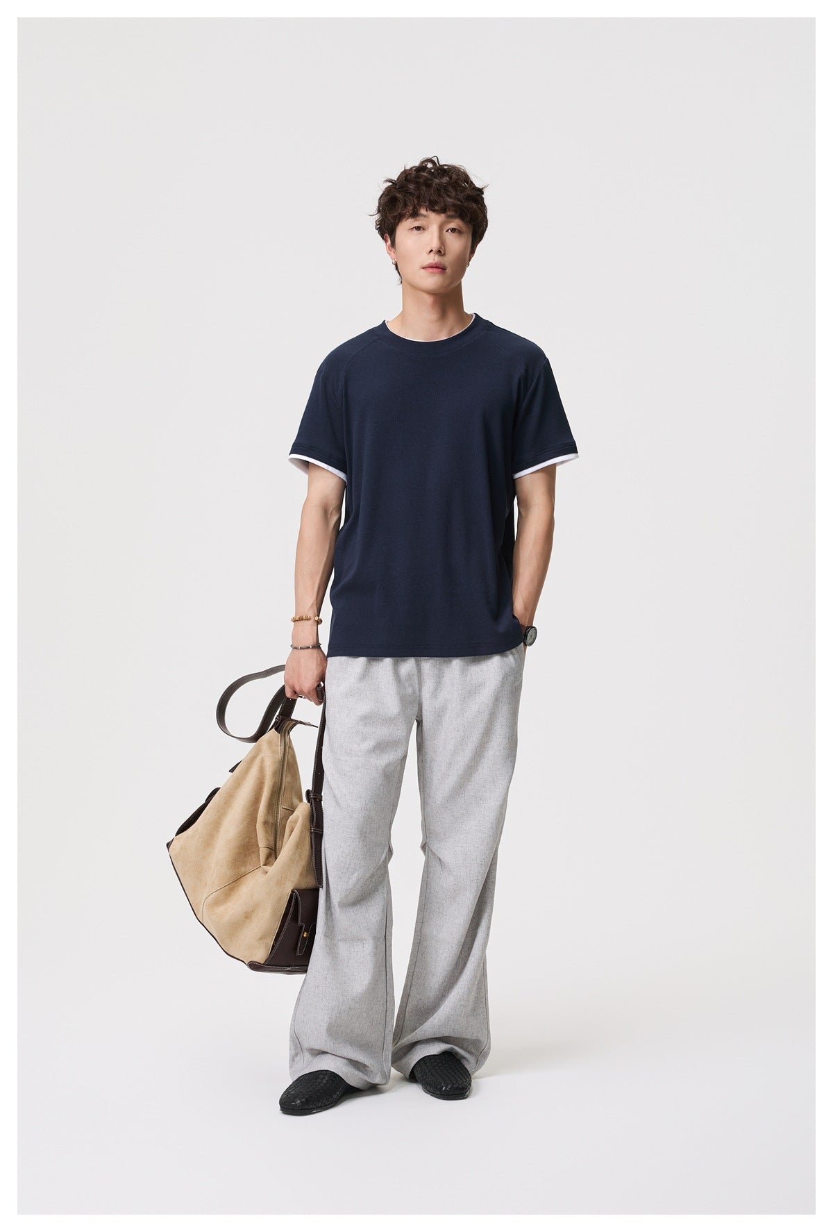 Full-length front view of a model wearing a navy T-shirt with white sleeve-cuff trim.