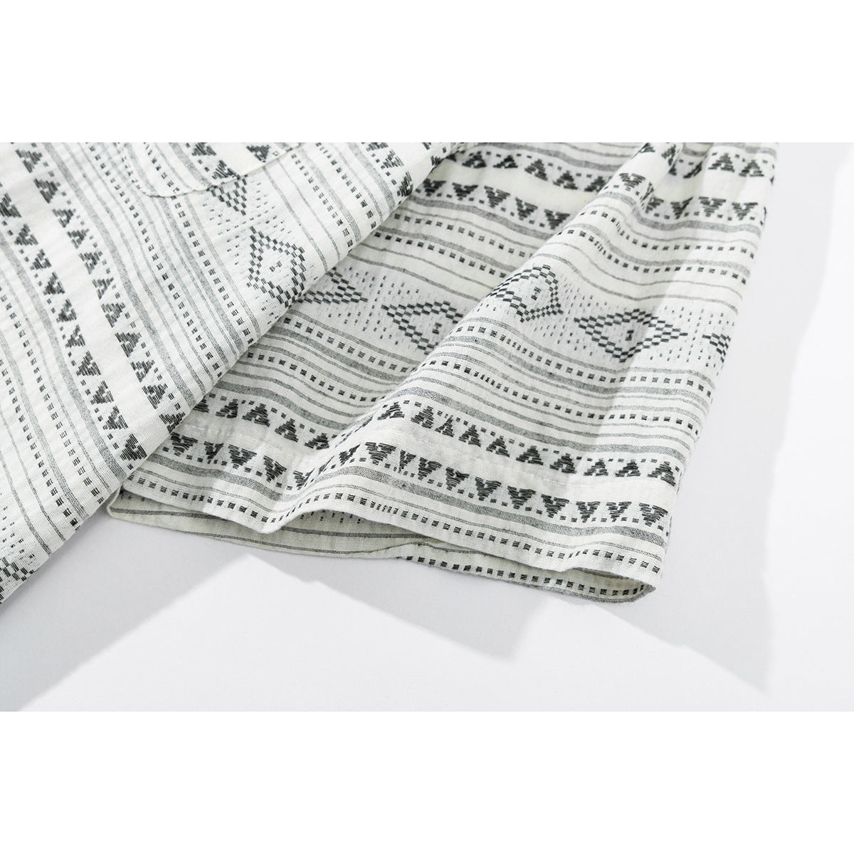 Close-up of the hem and patterned fabric of a white shirt with black geometric stripes.