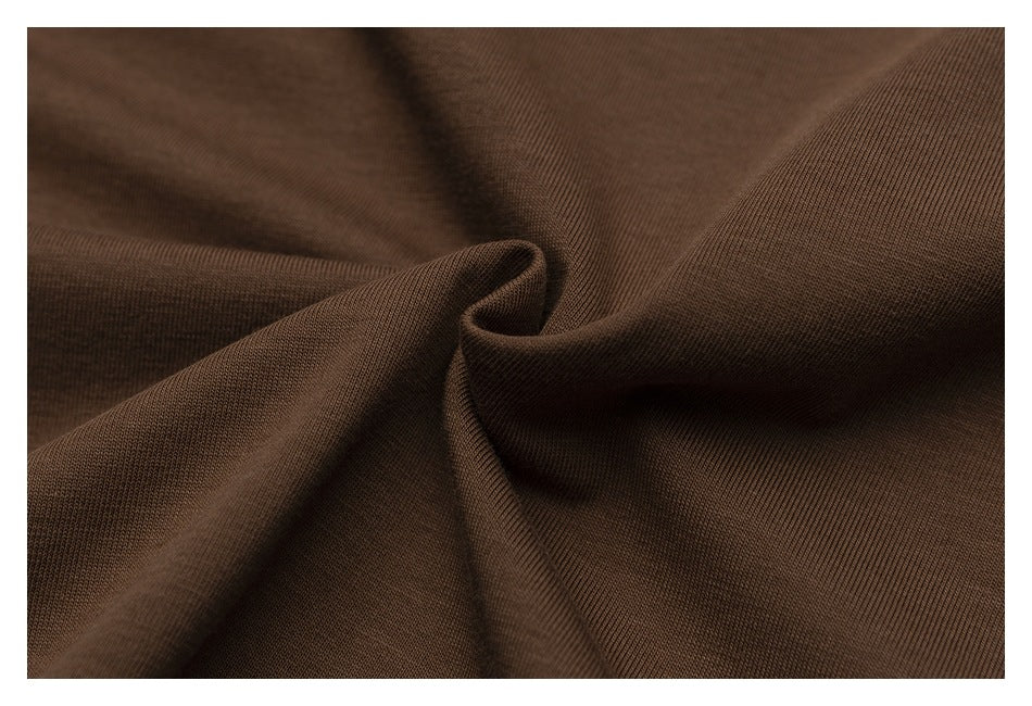 Close-up of plain dark brown fabric gathered into soft folds, showing its fine surface texture.