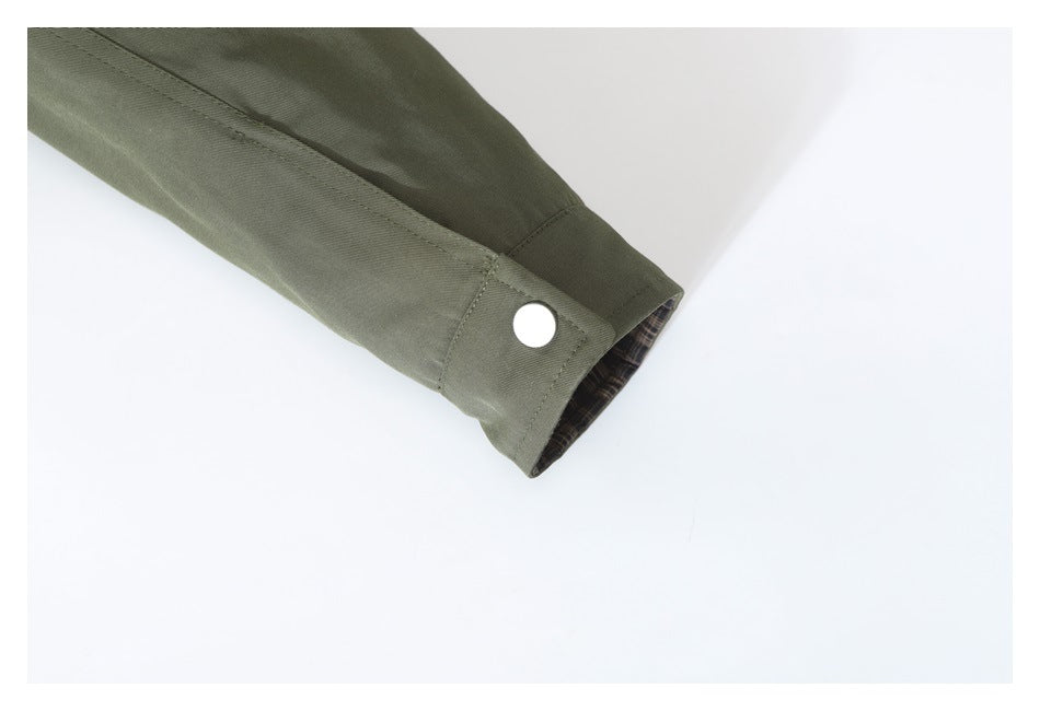 Olive jacket sleeve cuff with a silver snap and a glimpse of dark plaid lining.