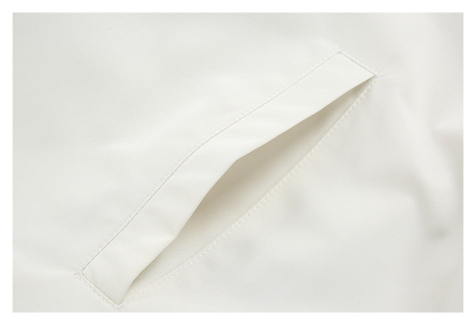 Close-up of a diagonal welt pocket on a white garment.