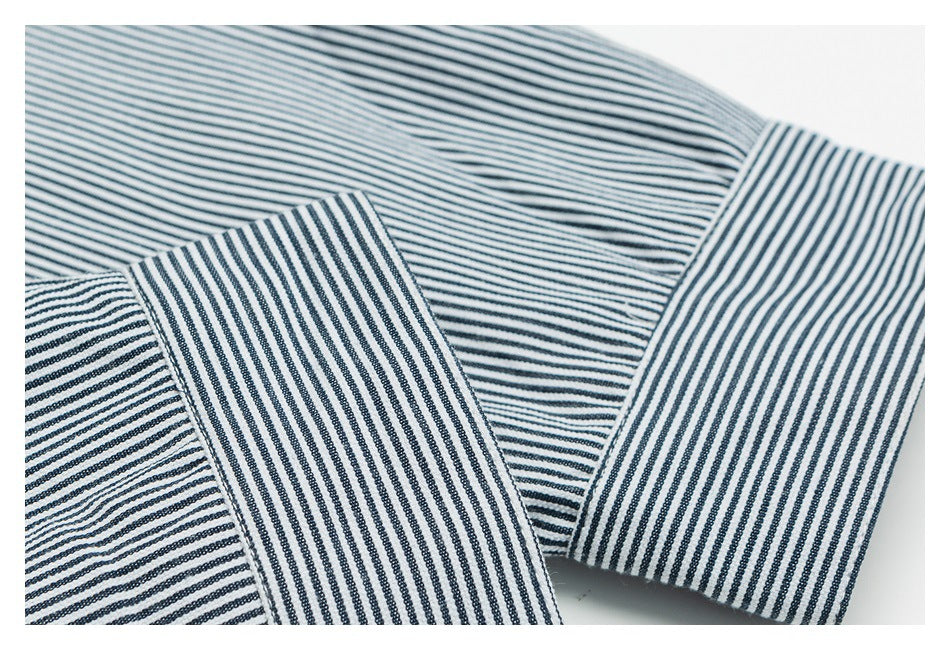 Close-up of white fabric with narrow navy stripes, showing folded and cuff-like sections.