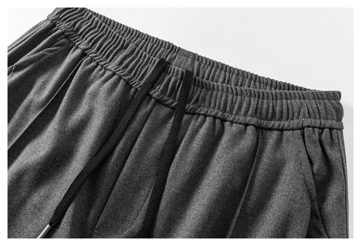 Close-up of charcoal-gray pants with a gathered elastic waistband and long black drawstrings.