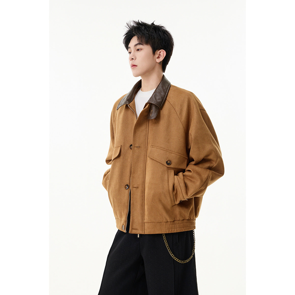 Three-quarter view of a model wearing a camel-brown jacket with a dark contrast collar and buttoned flap pockets.