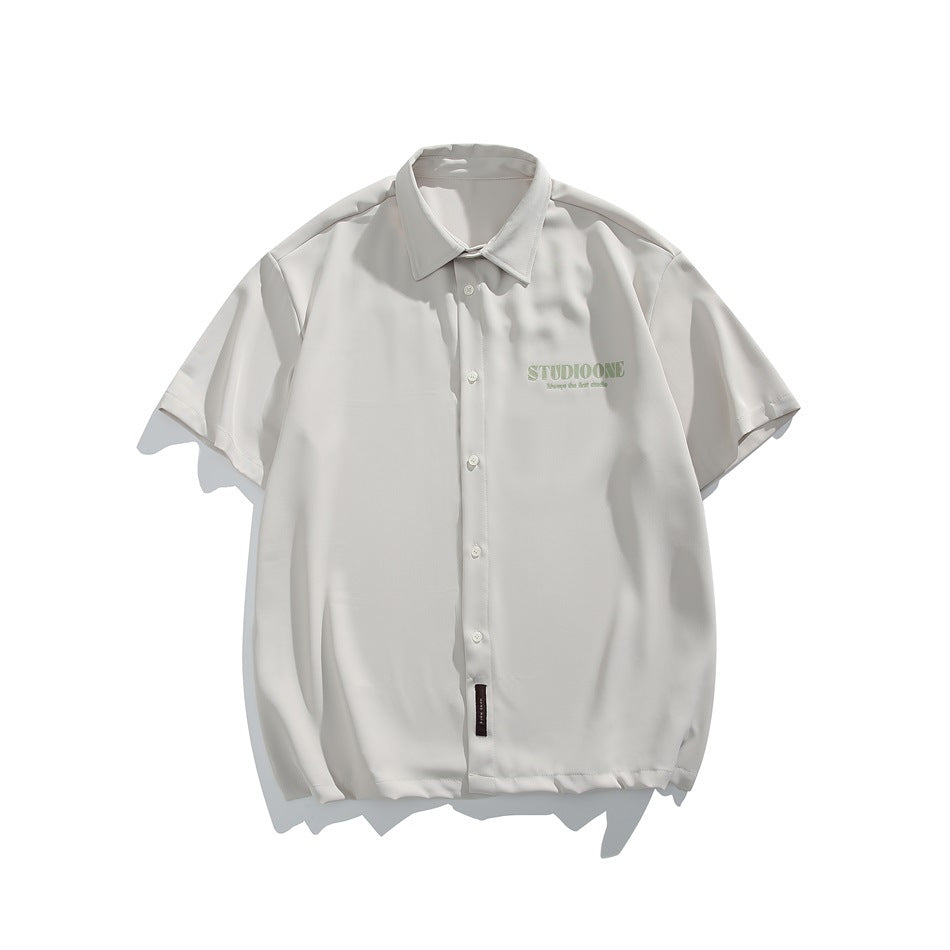 Beige short-sleeve button-up shirt with collar and small green chest print, flat lay front view