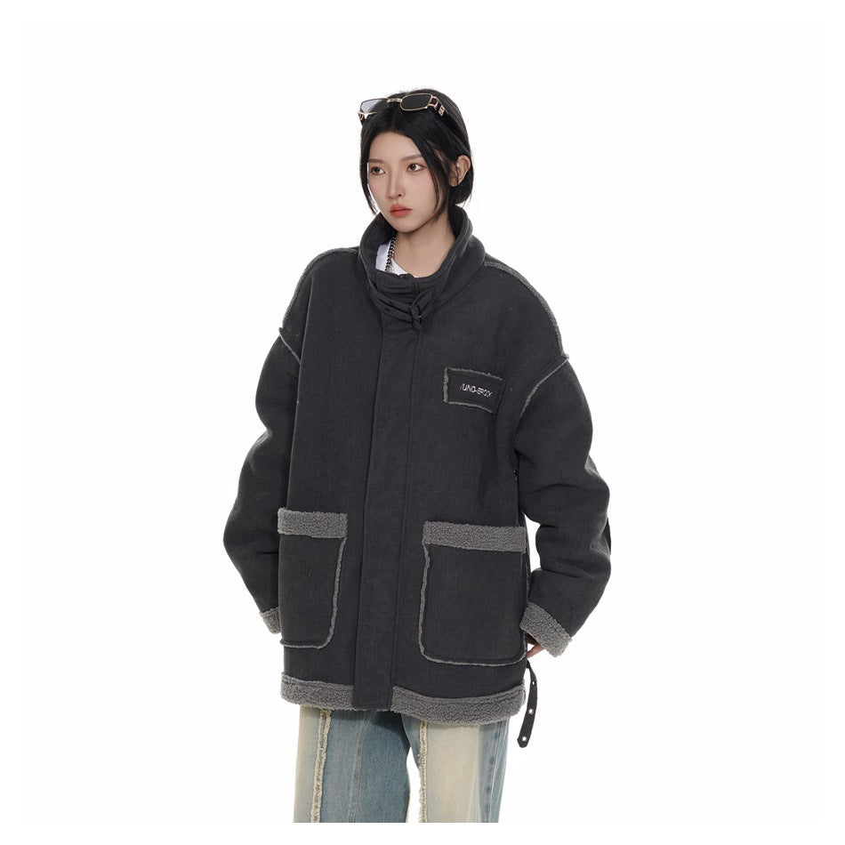 Model wearing an oversized charcoal jacket with a high collar, front patch pockets, gray trim and a small chest patch.