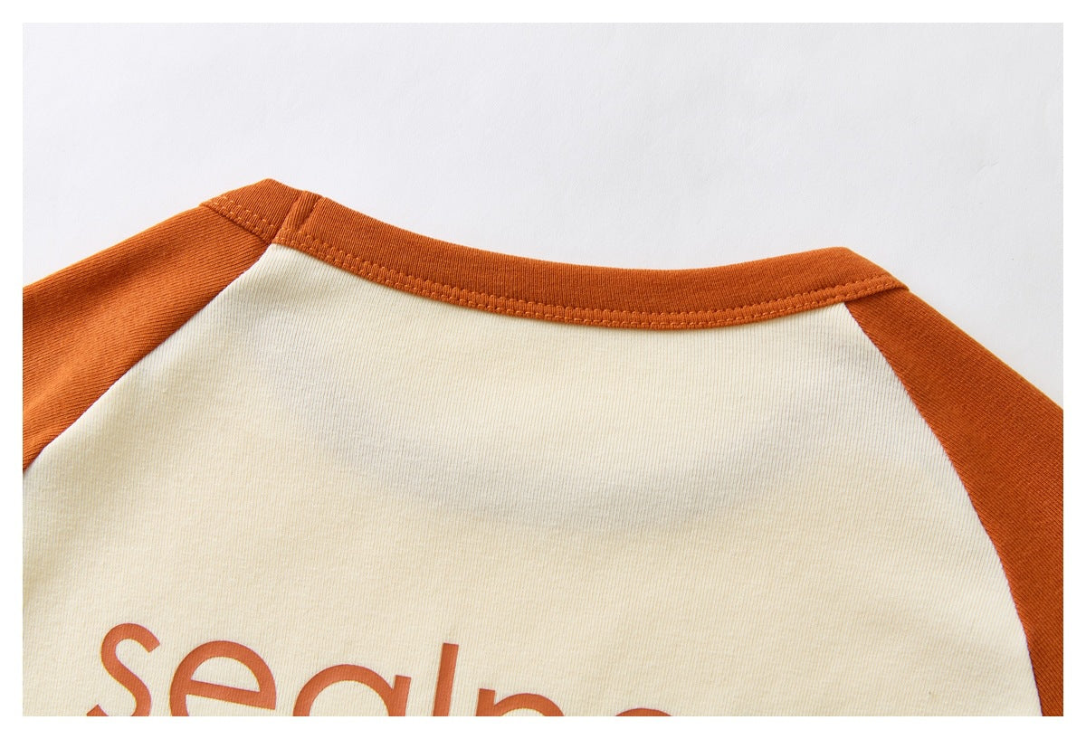 Close-up of the cream shirt's back neckline with rust-orange raglan sleeves and partial orange lettering.