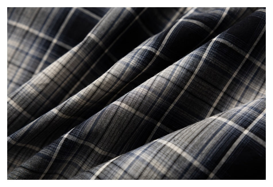 Close-up of folded black, gray, and beige plaid fabric with intersecting windowpane checks.