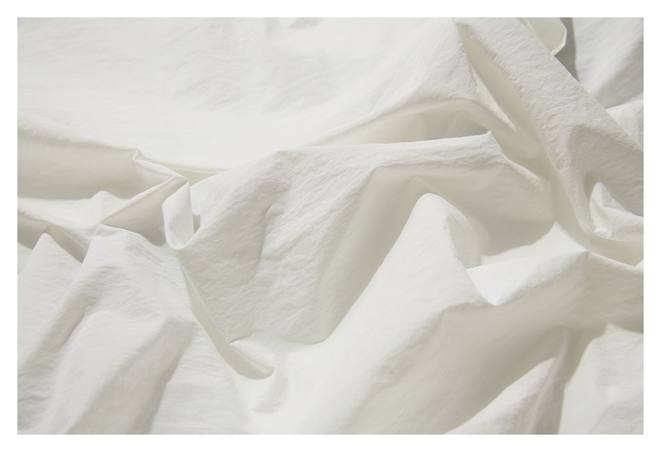 Close-up of loosely folded off-white fabric showing its surface texture.