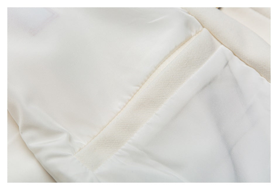 Close-up of a white garment showing a diagonal textured seam and stitched fabric panels.