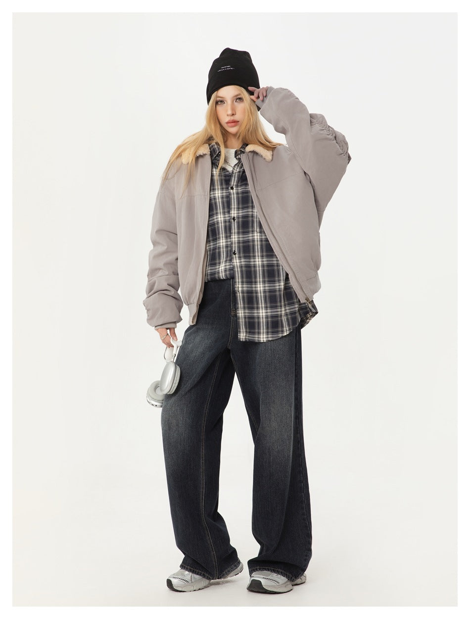 Model wearing a light gray shearling-collar bomber jacket over a plaid shirt and dark wide-leg jeans.