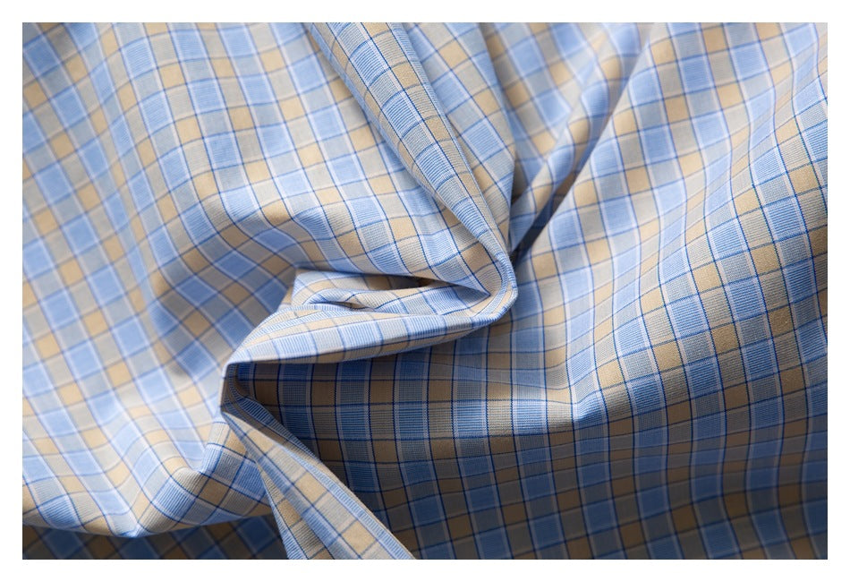 Close-up of the shirt's blue and tan plaid fabric draped in folds.