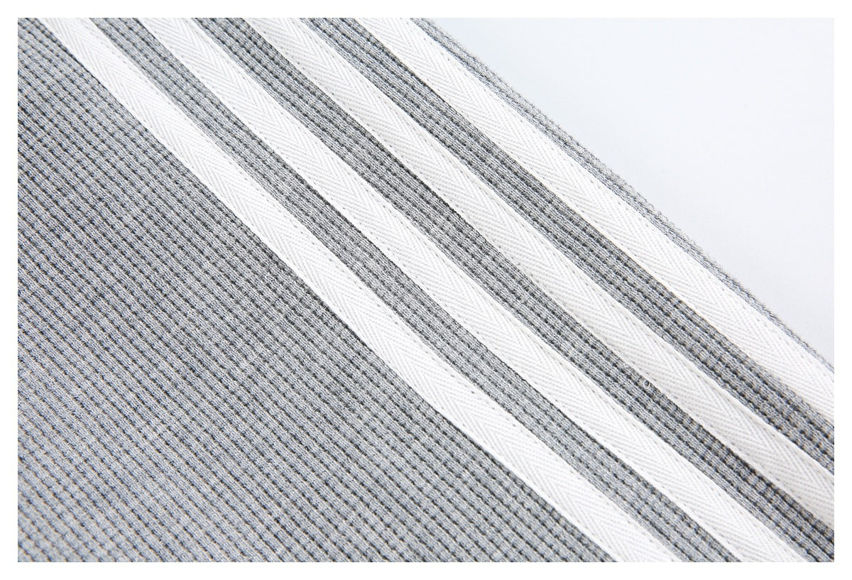 Close-up of three white stripes running diagonally across gray textured fabric.