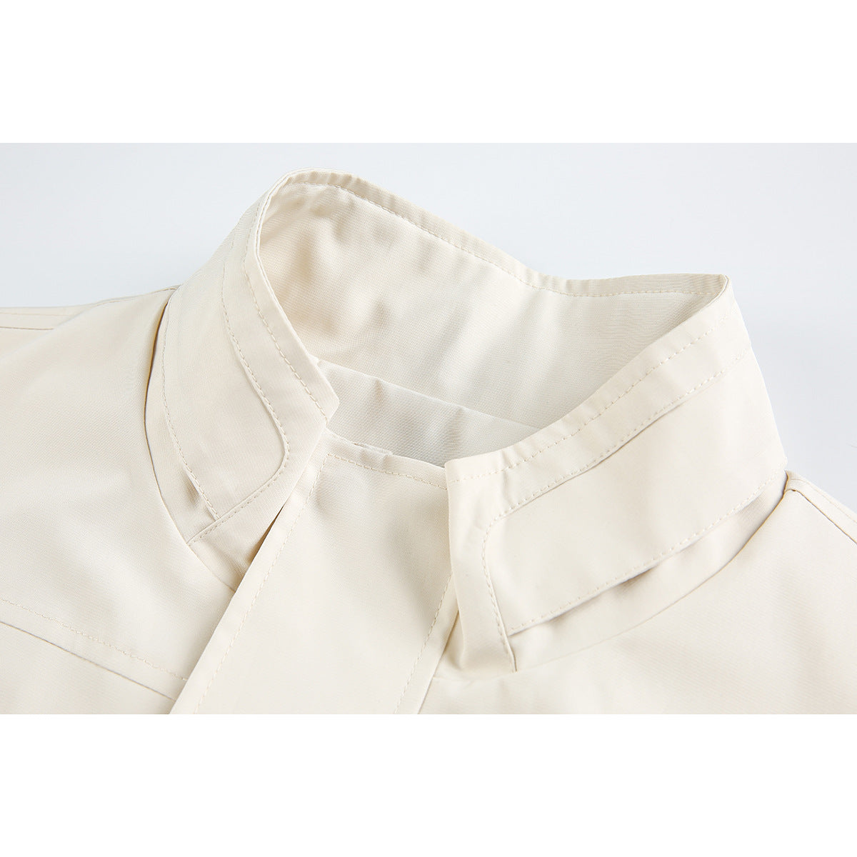 Close-up of a cream jacket's high collar and stitched neckline.
