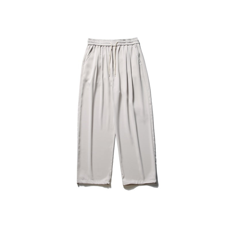 Light beige wide-leg drawstring pants with elastic waist, front pleats and side pockets, flat lay on white