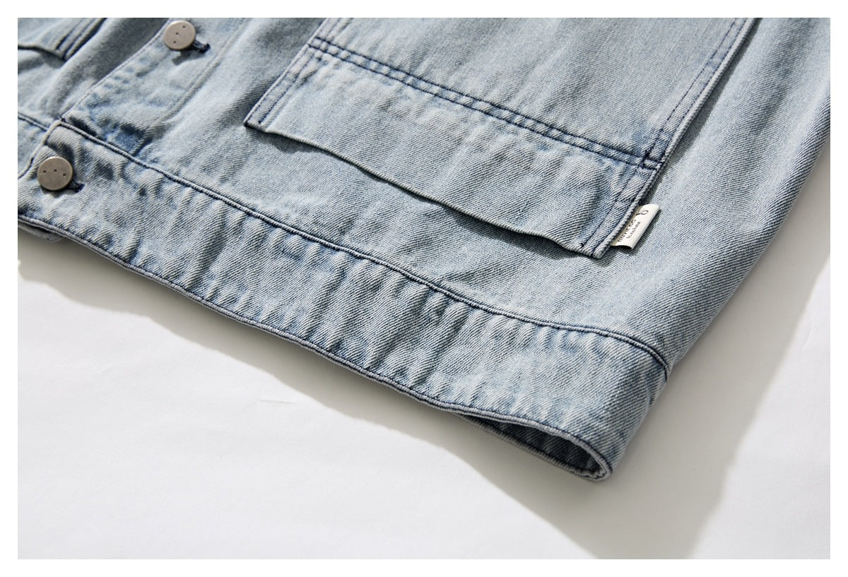 Close-up of the lower front of a light blue washed denim jacket, showing a large pocket and hem.