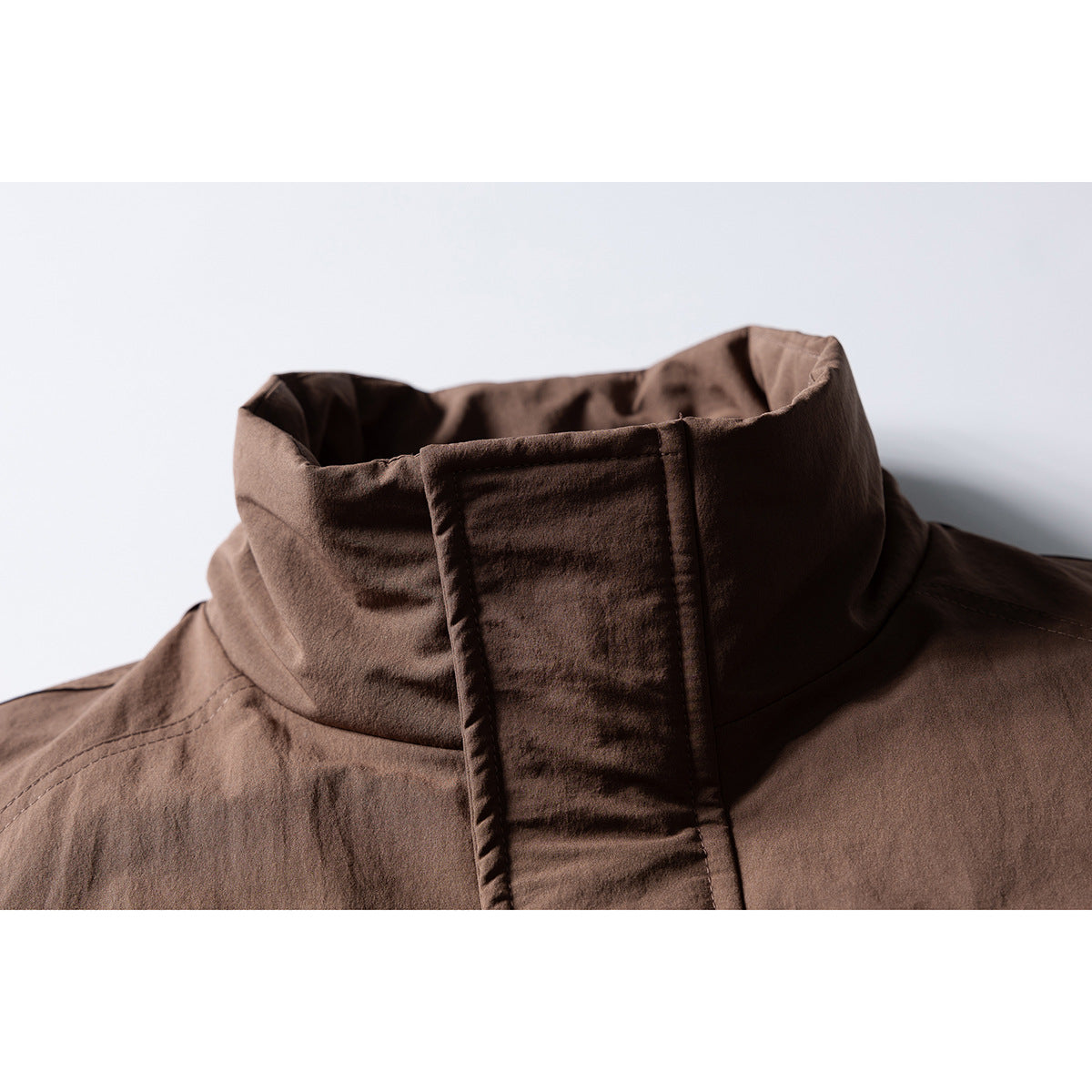Close-up of a brown jacket's tall stand collar and covered front placket.