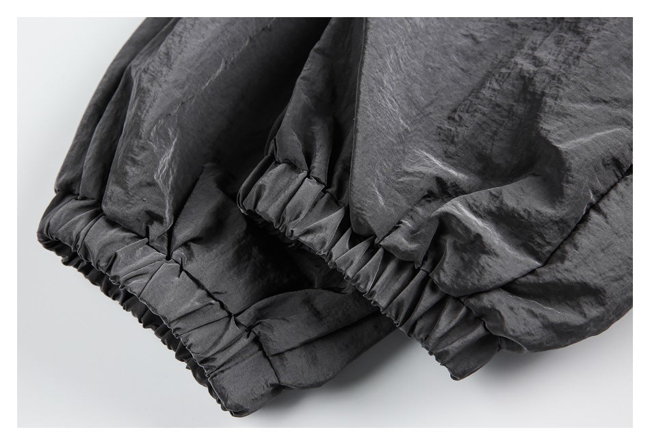 Close-up of gathered elastic edges and overlapping panels on a dark charcoal garment.